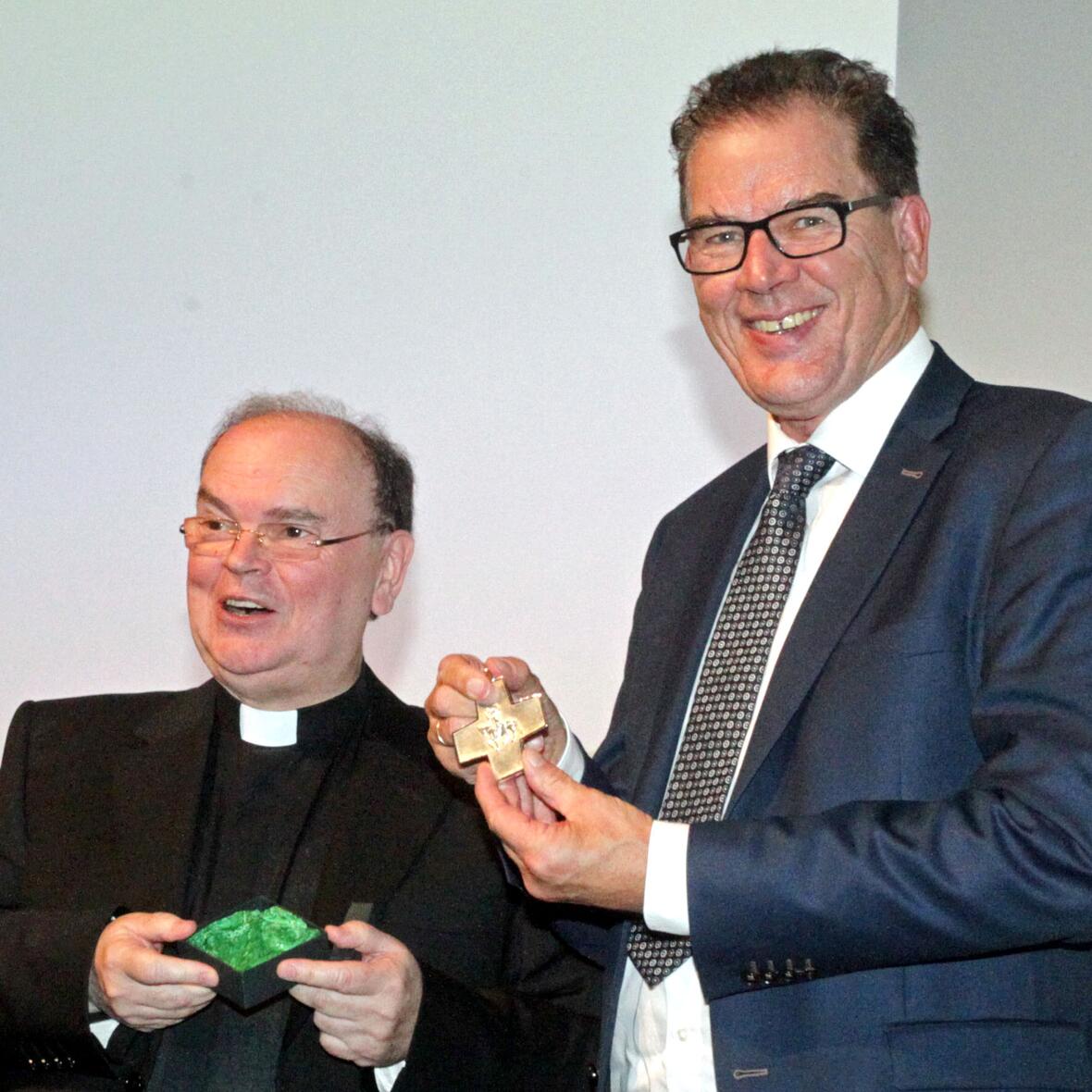 Diözesanadministrator Bertram Meier überreicht Minister Müller das Ulrichskreuz.