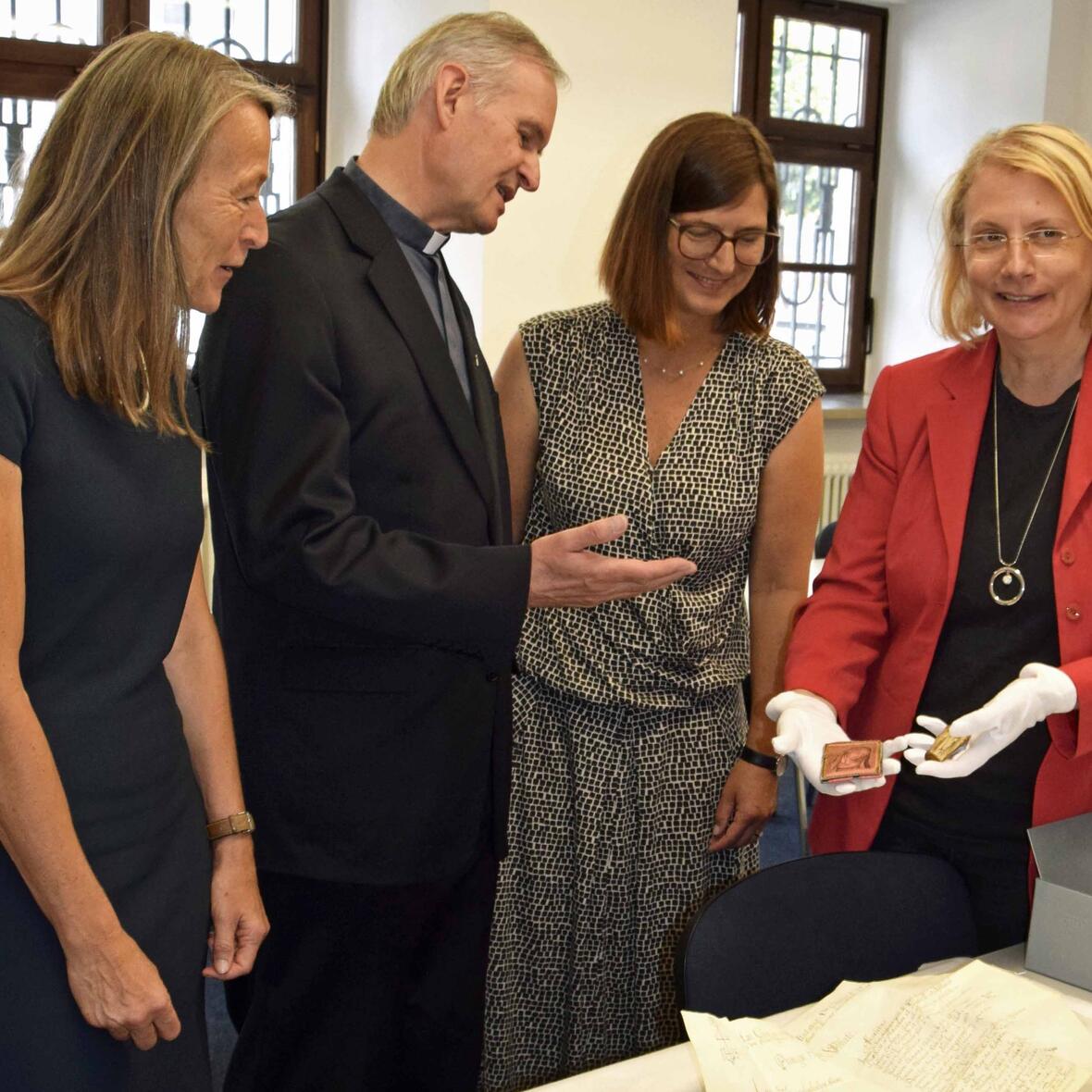 Historikerin und Archäologin Birgit Kata (r.) zeigt der Leiterin des Staatlichen Bauamtes Cornelia Bodenstab (l.) und Stadtpfarrer Monsignore Dr. Bernhard Ehler den von Restauratorin Ursula Dekker-Sturm gesichteten Inhalt der zweiten Zeitkapsel. (Foto: Sabine Verspohl-Nitsche / pdke)