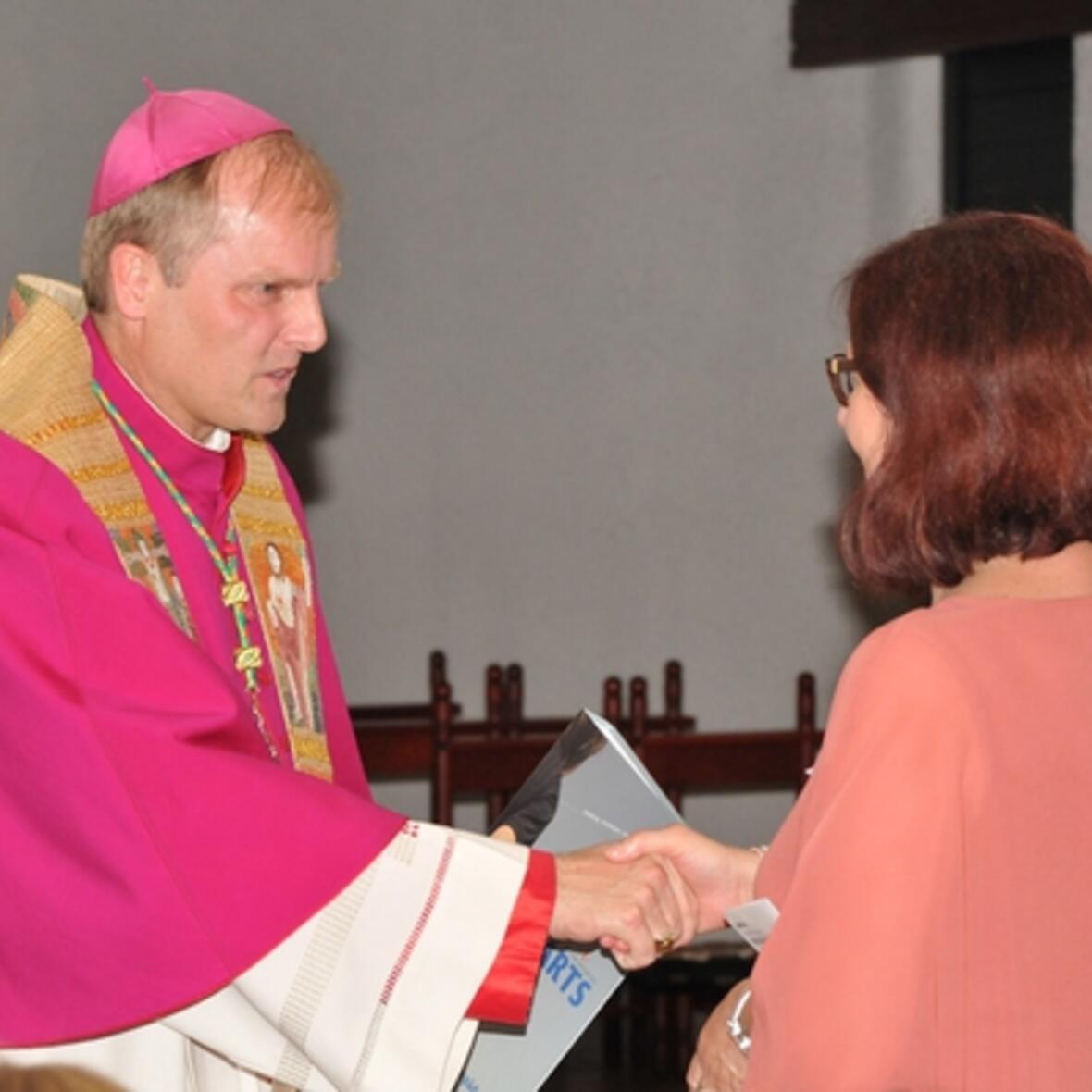 Weihbischof Wörner überreicht einer Berufspraktikantin das Handbuch, das als Begleiter für die religionspädagogische Arbeit sowie die Fort- und Weiterbildung dienen soll. (Foto: Schule und Religionsunterricht)