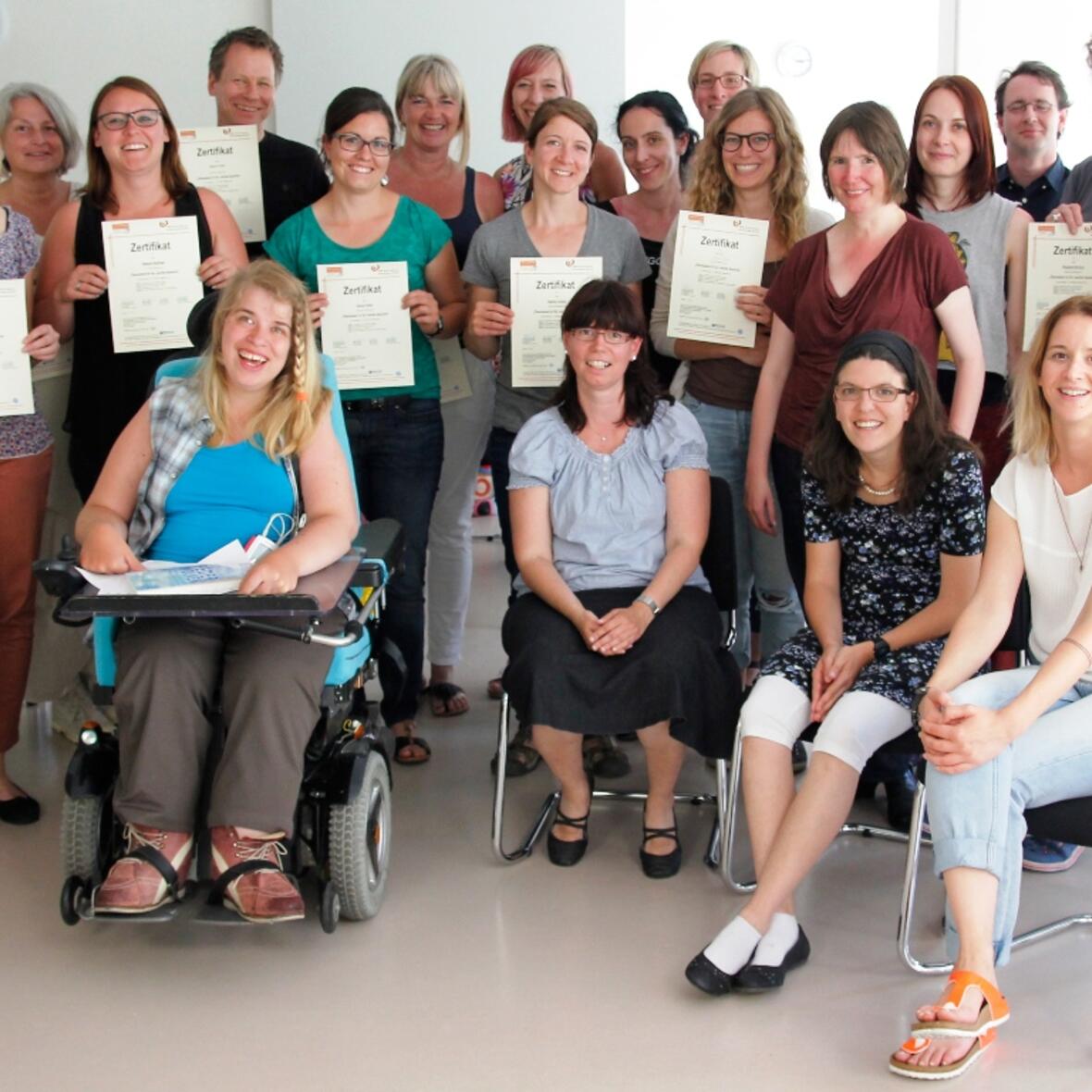 Nach sieben Tagen Ausbildung halten sie ihr Zertifikatszeugnis als Übersetzer/-in für die Leichte Sprache in der Hand. In der ersten Reihe sitzen (von links nach rechts) die drei Prüferinnen Andrea Käb, Maria Hütter und Tanja Greisel, Betroffene, die die übersetzten Texte prüfen, ob sie wirklich verständlich sind und den Kriterien der Leichten Sprache entsprechen. Kristina Wehner (vorne rechts) hat als Dozentin und Übersetzerin für Leichte Sprache sowie Prüferbeauftragte den Kurs geleitet. (Foto: Caritas Augsburg / Bernhard Gattner)