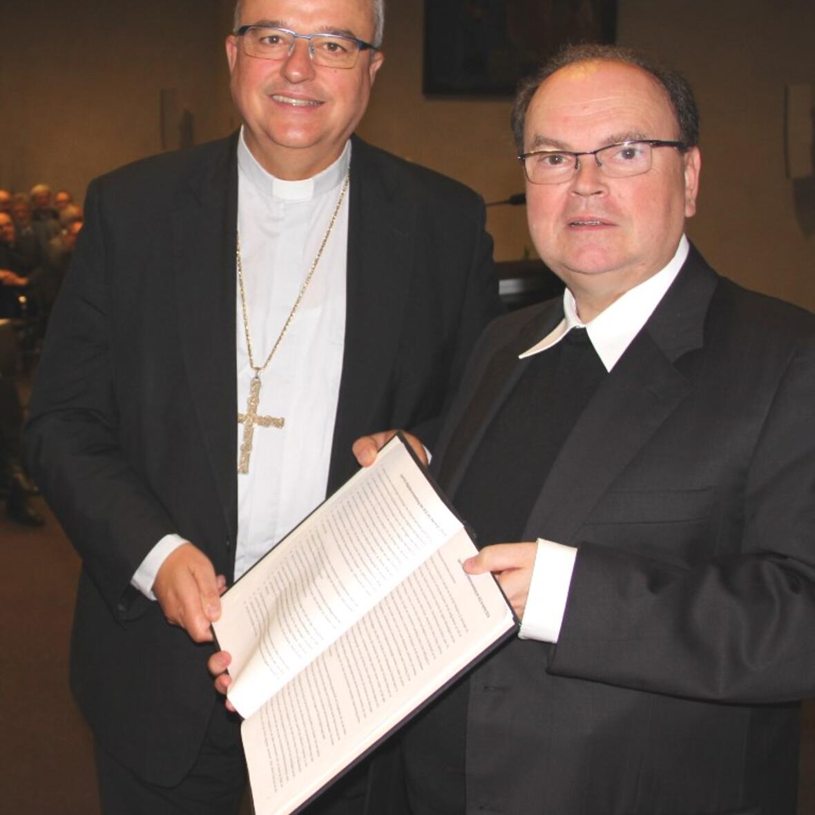 Bischof Karl-Heinz Wiesemann (links) übergibt symbolisch zur Weiterarbeit dem Vorsitzenden der ACK Bayern, Prälat Bertram Meier, das Wort der ACK zu 500 Jahre Reformation. (Foto: ACK/Witzenbacher)