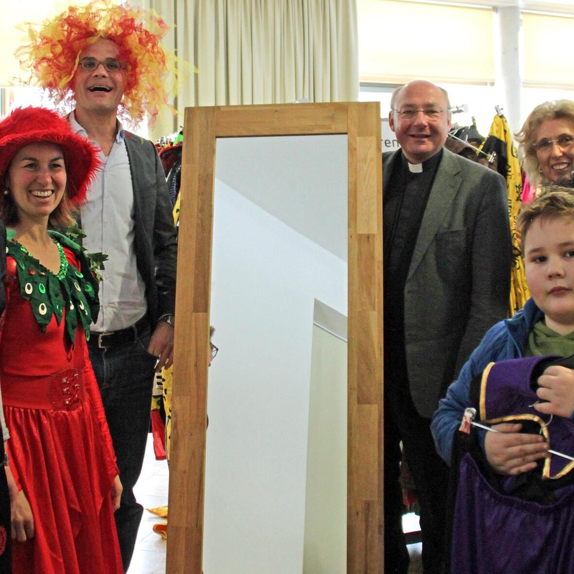 Pfarrer Dr. Ulrich Lindl (rechts neben Spiegel) und Gregor Uhl (links) eröffnen mit dem ehrenamtlichen Team aus Lauingen und Kunden die diesjährigen Secondhand-Faschingsmärkte der aktion hoffnung. (Foto: Karin Stippler / aktion hoffnung)