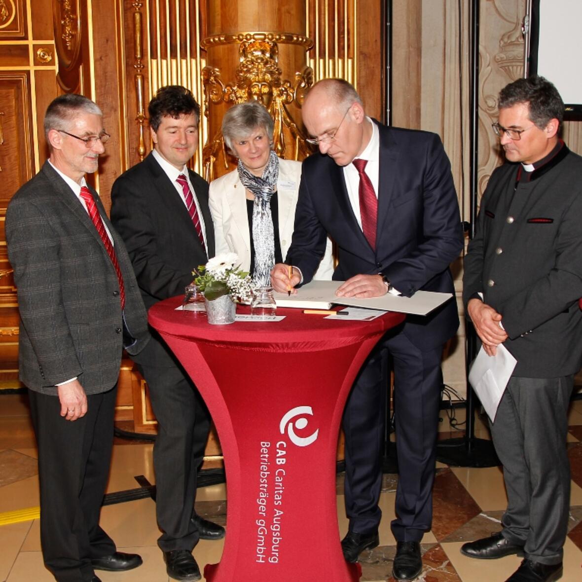 Oberbürgermeister Dr. Kurt Gribl trug als erster seine Dankesworte in das große Erinnungsbuch anlässlich der Bombenevakuierung ein. Foto: Caritas Augsburg/Bernhard Gattner. 