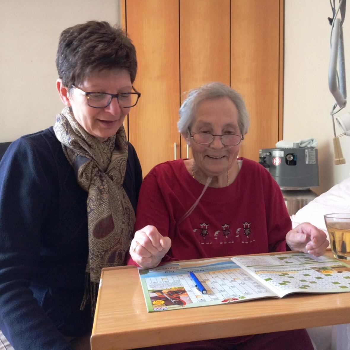 Die Pflegedienstleiterin Daniela Renzmann sitzt neben Lisa Lebold, die ein Kreuzworträtsel löst. (Foto: Dagmar Weindl)