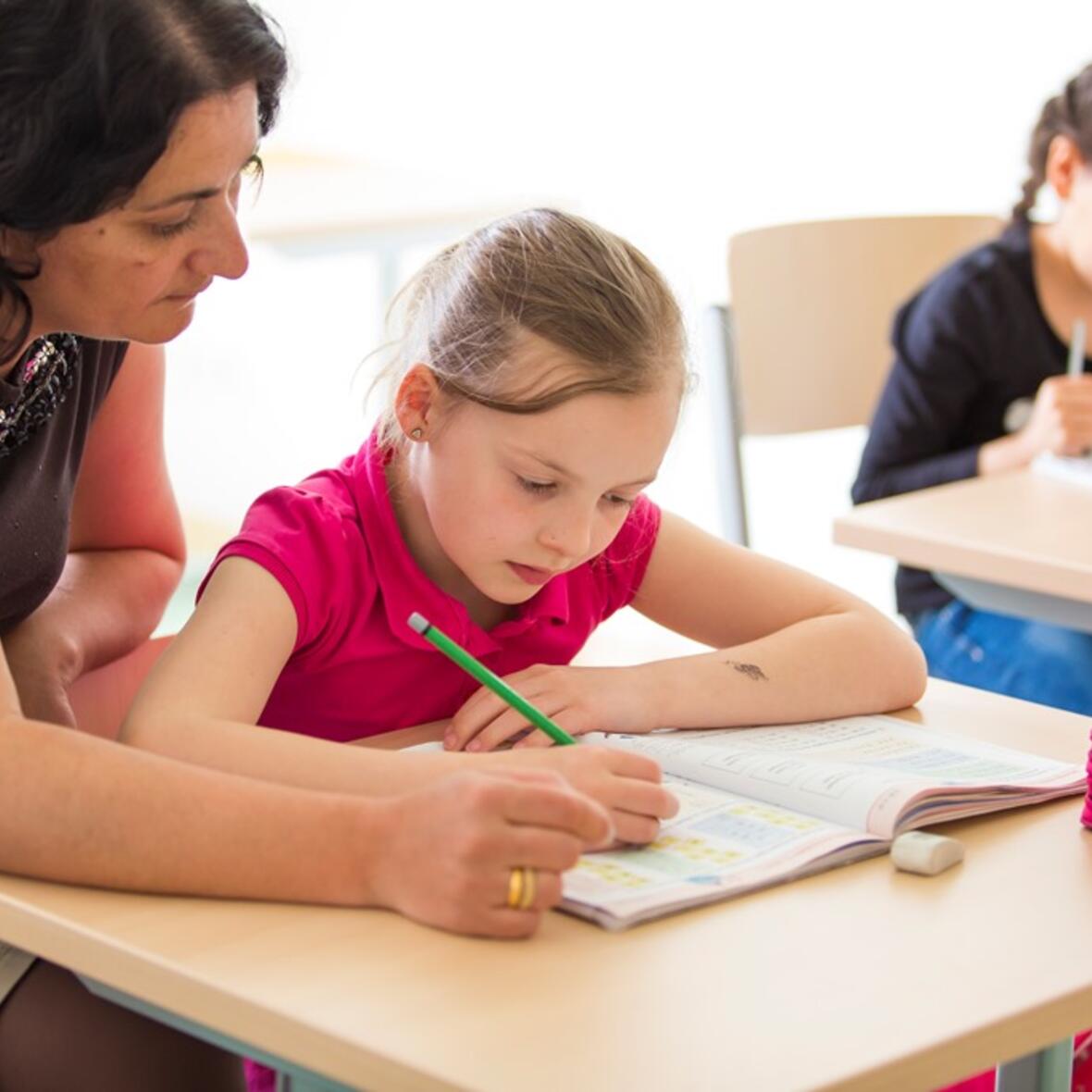 Mitarbeiterinnen des Familienzentrums unterstützen Kinder bei den Hausaufgaben. (Foto: KJF)