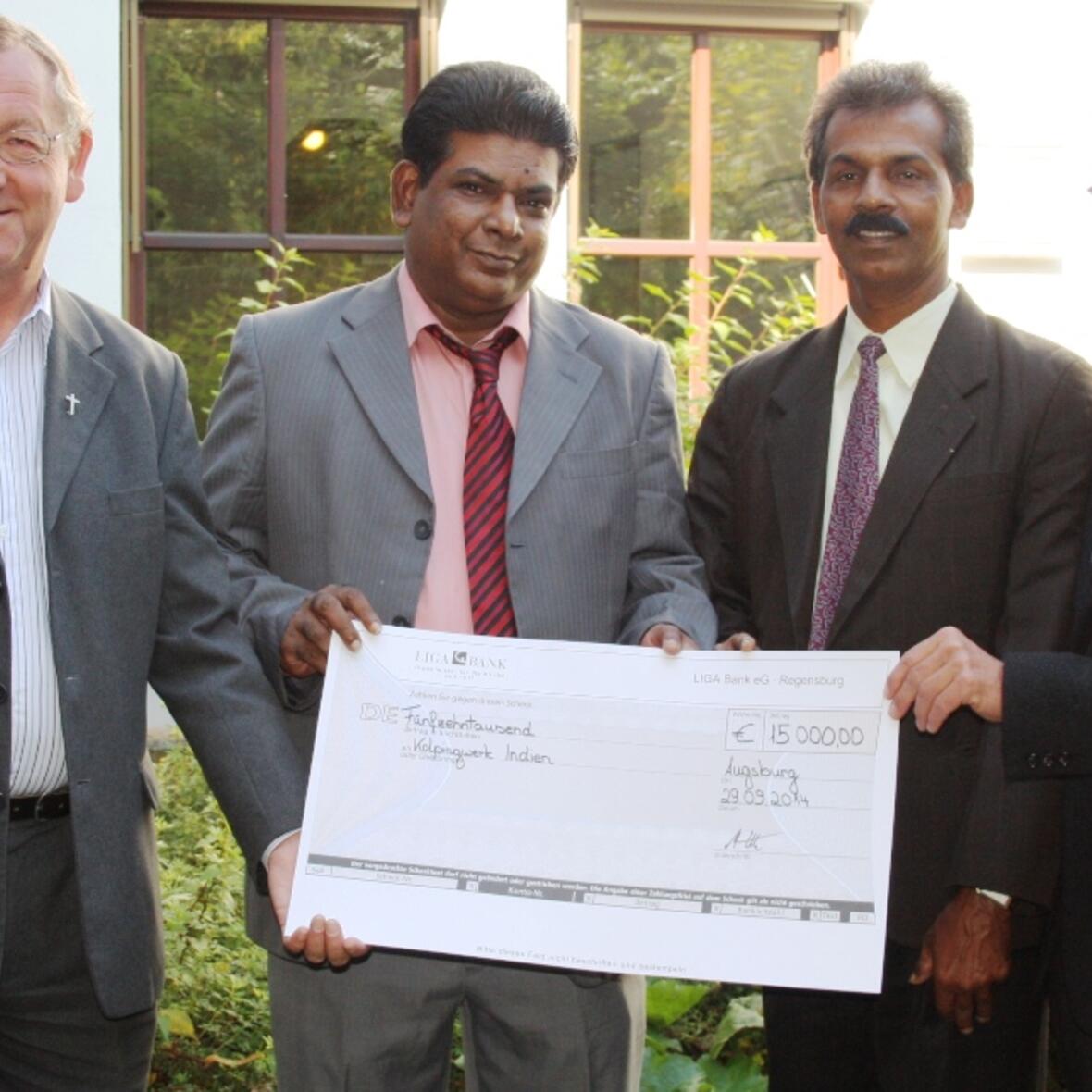 Freude bei den Gästen aus Indien über den Spendenscheck, den der Augsburger Kolping-Diözesanpräses Alois Zeller (links) und Werner Moritz, Geschäftsführer der Kolpingstiftung-Rudolf-Geiselberger (rechts), überreichten. (Foto: Kolping)