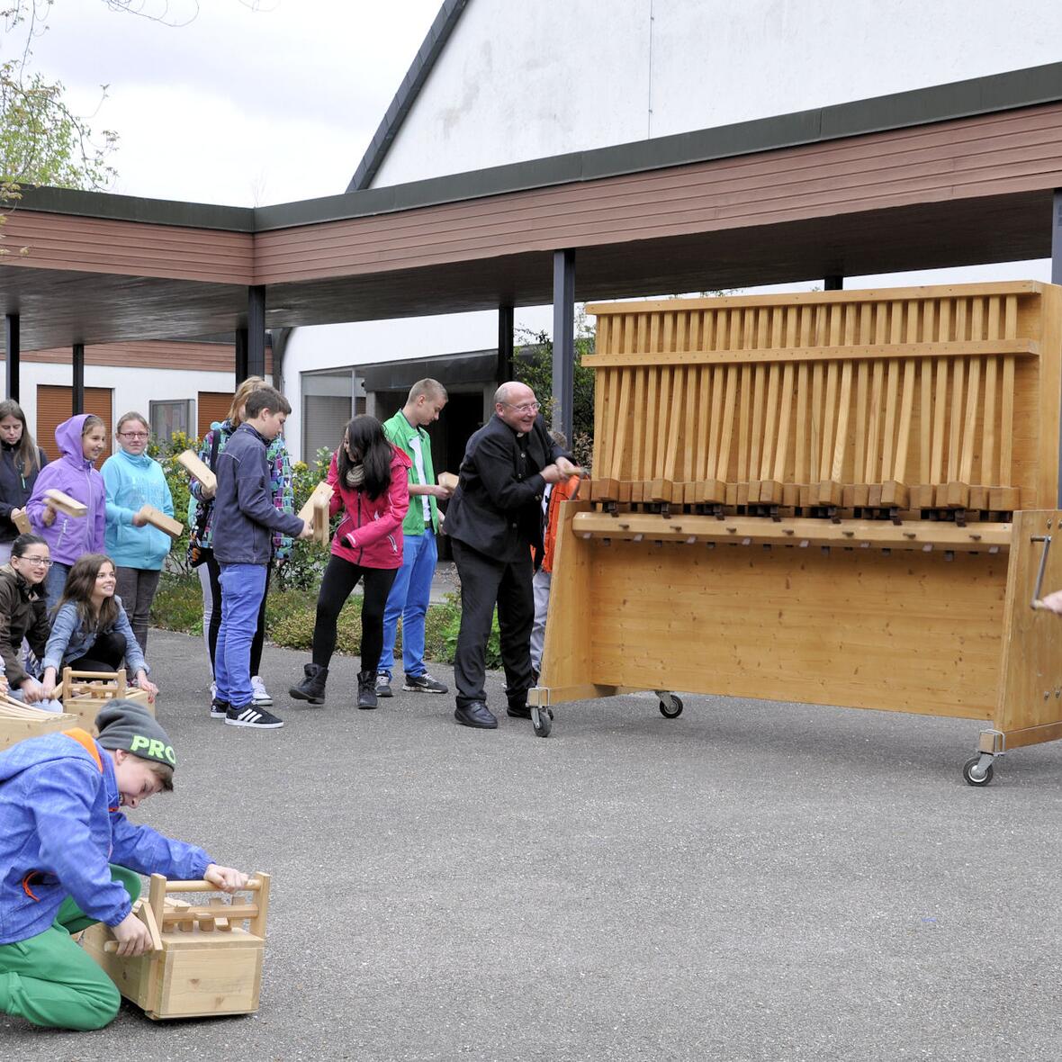 Pfarrer Dr. Ulrich Lindl, Leiter der Hauptabteilung III / Kirchliches Leben und Robert Sedlmayr, dritter Bürgermeister von Geltendorf, probierten sich im Rahmen der Eröffnungsveranstaltung an der wohl größten Rätsche der Welt aus. 