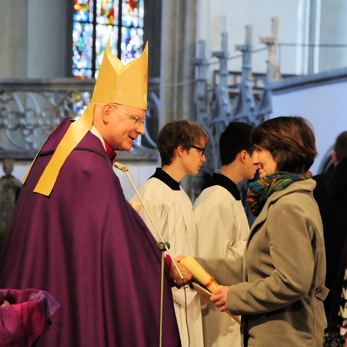 Eine Taufbewerberin überreicht Bischof Konrad das Empfehlungsschreiben für die Zulassung zu den Sakramenten.