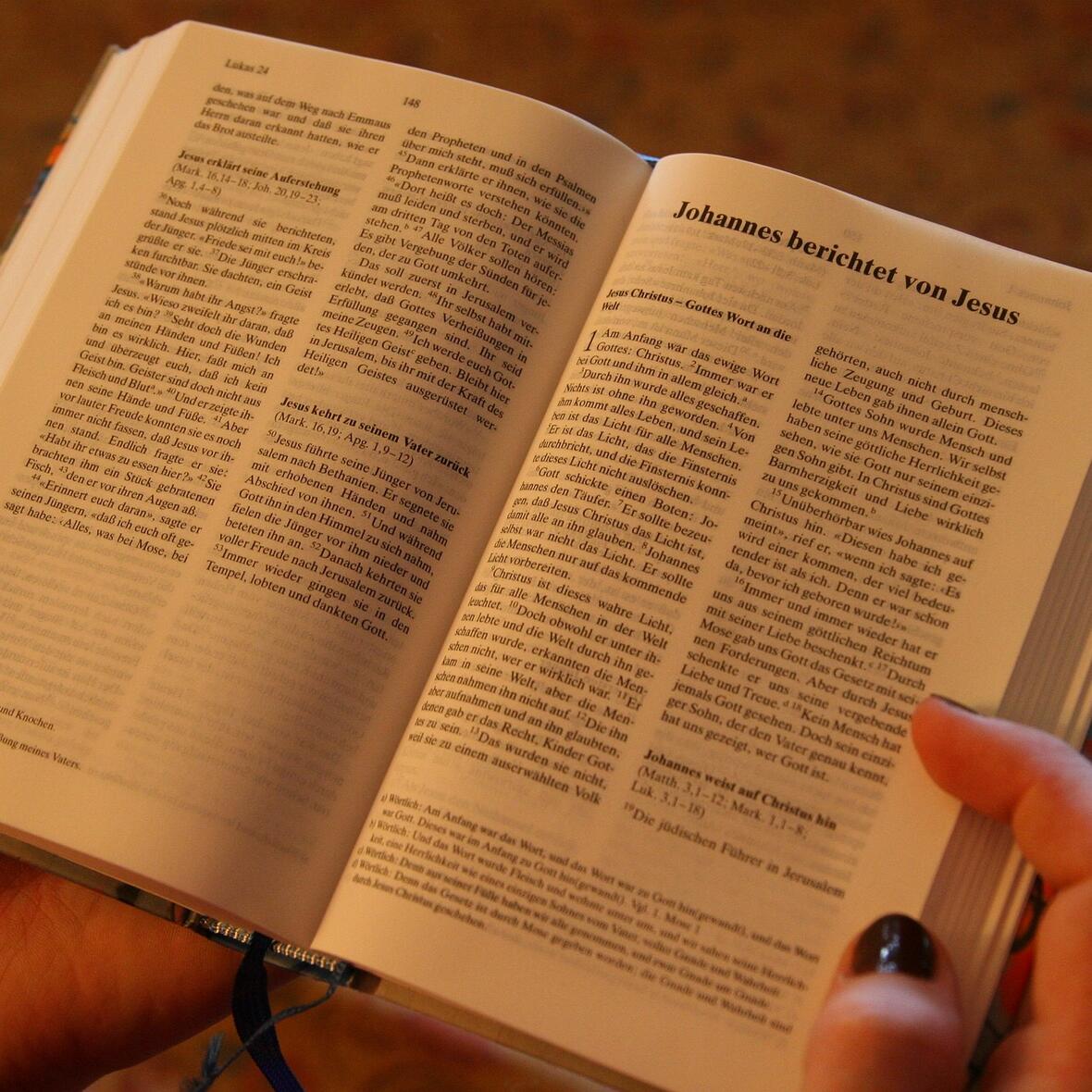 Eine Junge Frau hält eine deutsche Bibelausgabe in der Hand