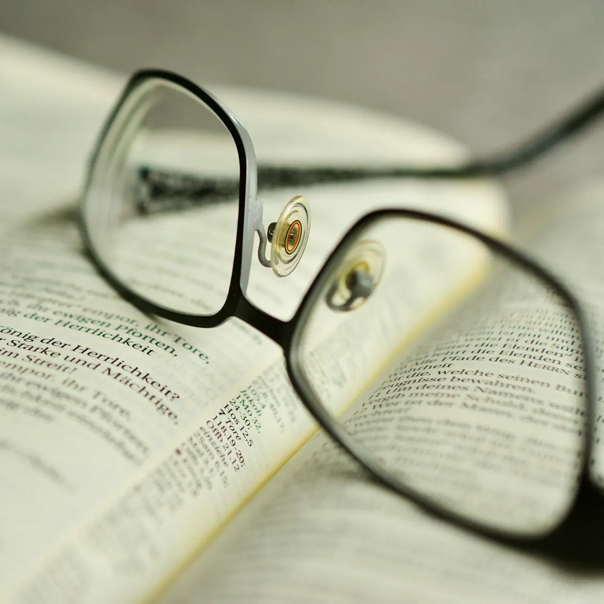 Eine Brille liegt auf einem aufgeschlagenem Buch. 