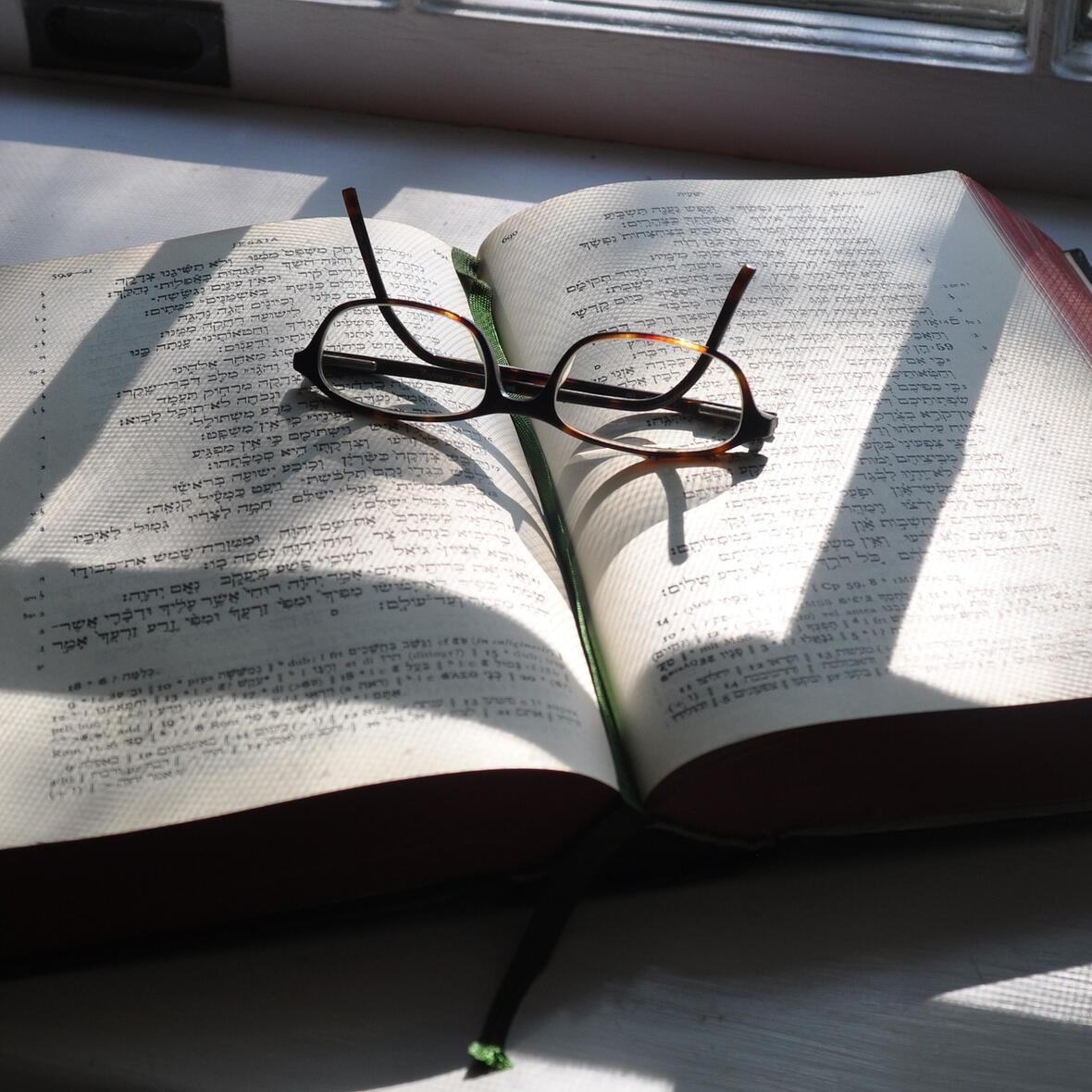 Aufgeschlagene Bibel, Brille liegt darauf