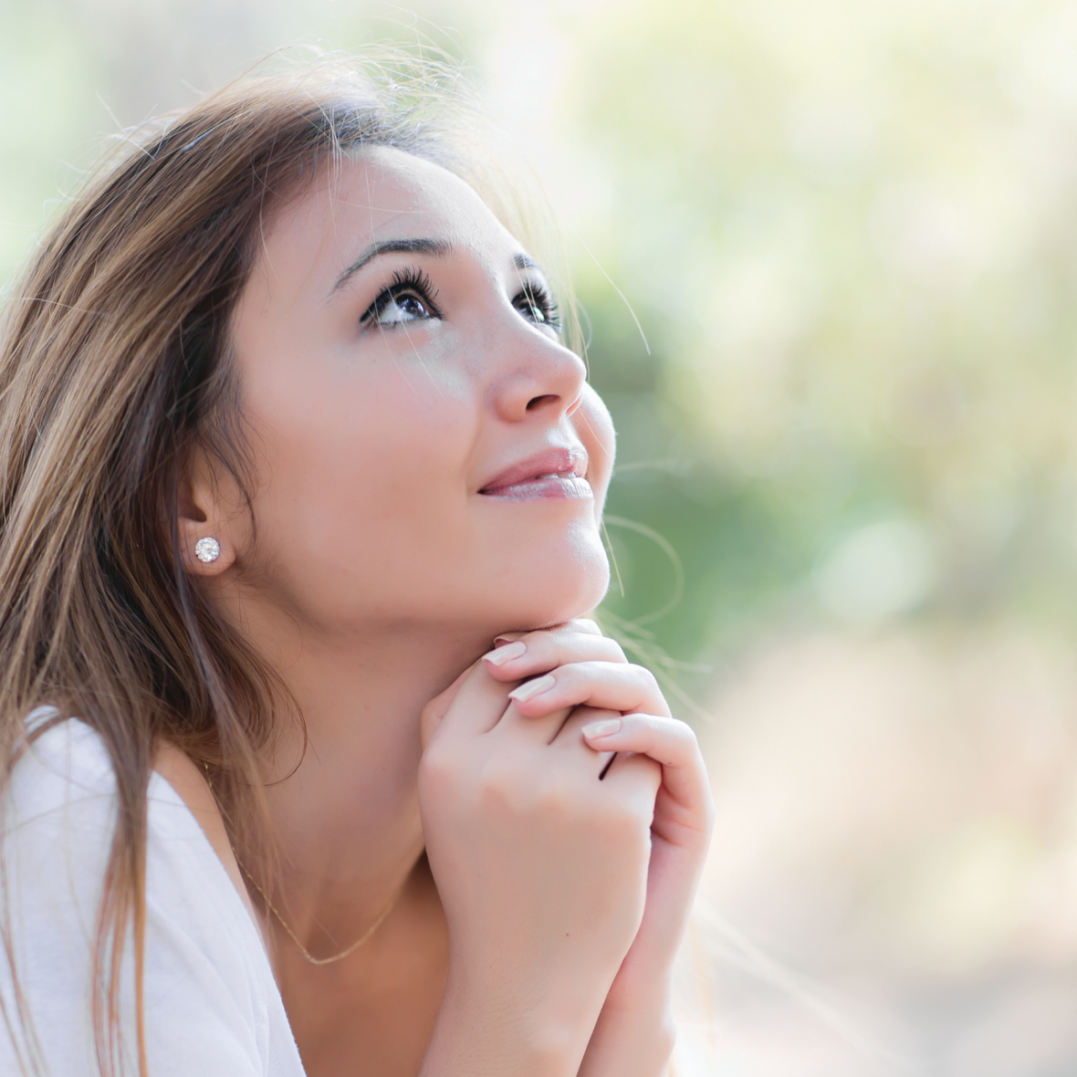 Eine junge Frau blickt nach oben, die Hände ineinandergelegt.