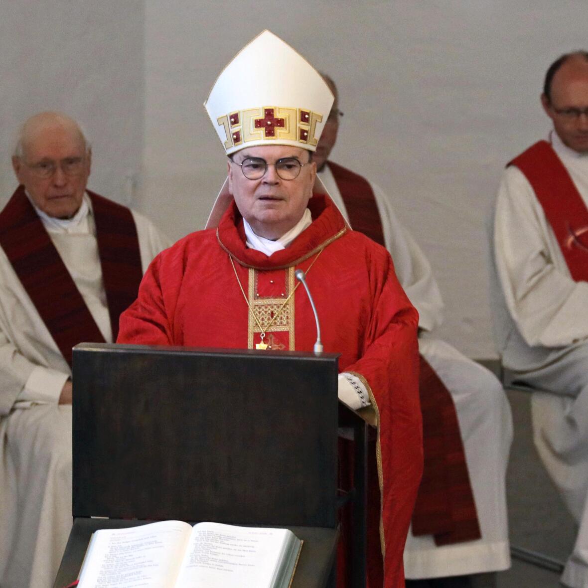 Bischof Bertram bei der Predigt. Neben ihm die Osterkerze. Im Hintergrund weitere Priester