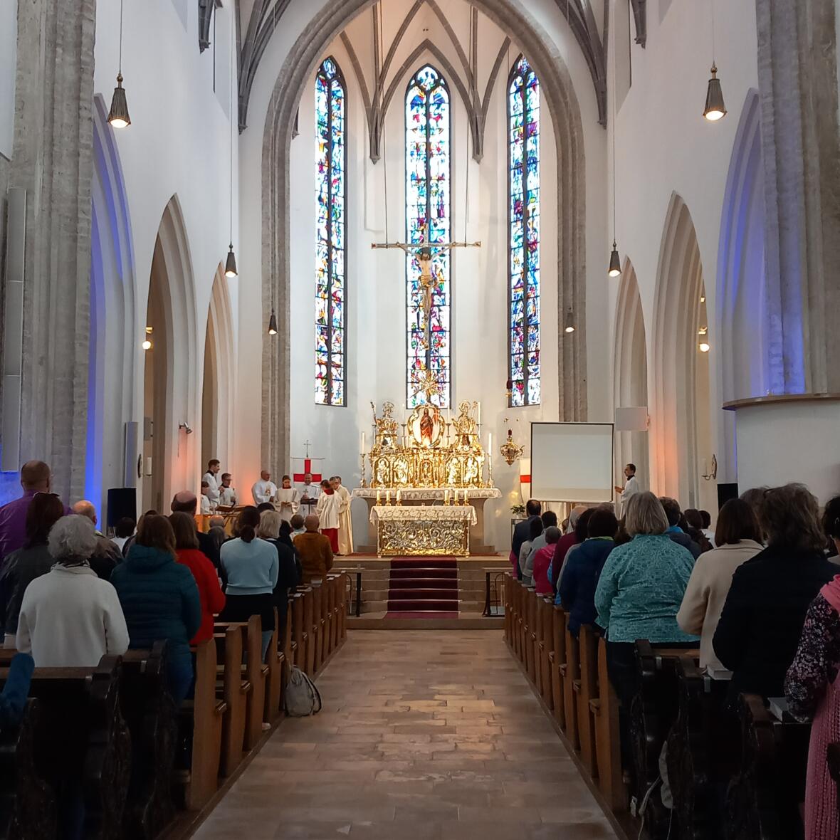 Menschen sitzen in den Bänken einer Kirche. 