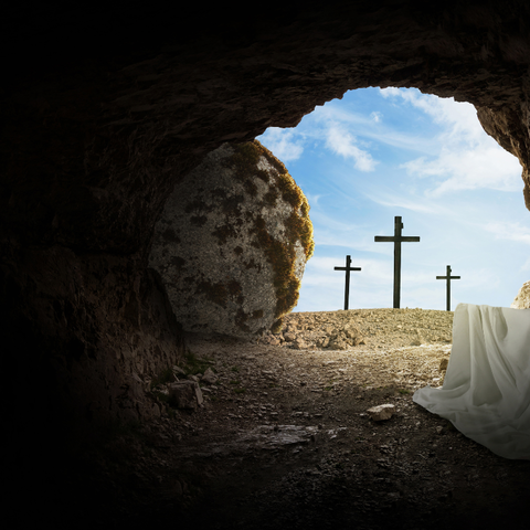 Dunkelheit, Blick durch runde Öffnung aus Felsengrab in Himmel, im Hintergrund drei Kreuze