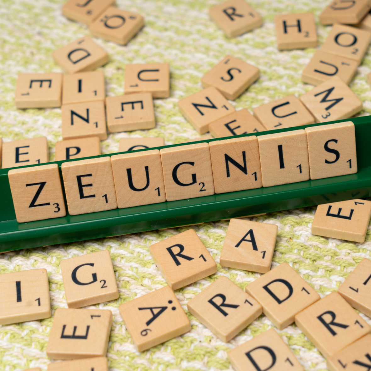 Ein Scrabble Brett mit dem gelegten Wort: Zeugnis, ringsum weitere Buchstaben Täfelchen