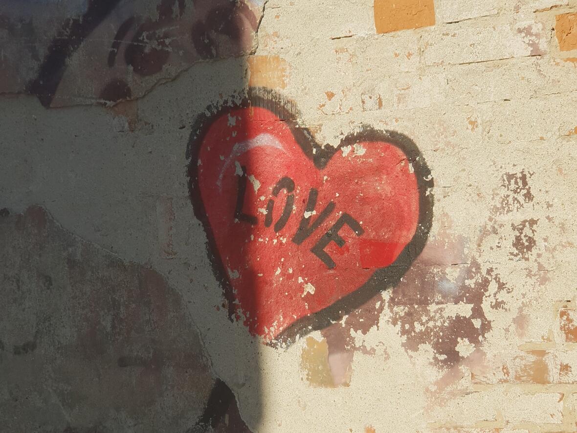 Auf einer Mauer ist ein gemaltes Herz mit der Aufschrift "LOVE".