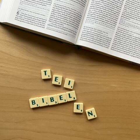 Unterhalb einer Bibel ist mit Scrabble Steinen das Wort: "Bibelteilen" gelegt