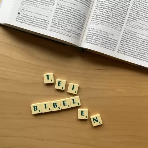 Unterhalb einer Bibel ist mit Scrabble Steinen das Wort: "Bibelteilen" gelegt