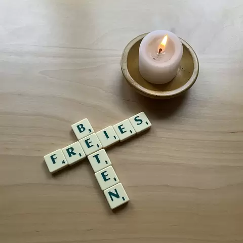 Neben einer Kerze ist mit Scrabble Steinen das Wort: "freies beten" gelegt