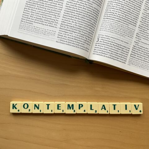 Unterhalb einer Bibel ist mit Scrabble Steinen das Wort: "Kontemplation" gelegt