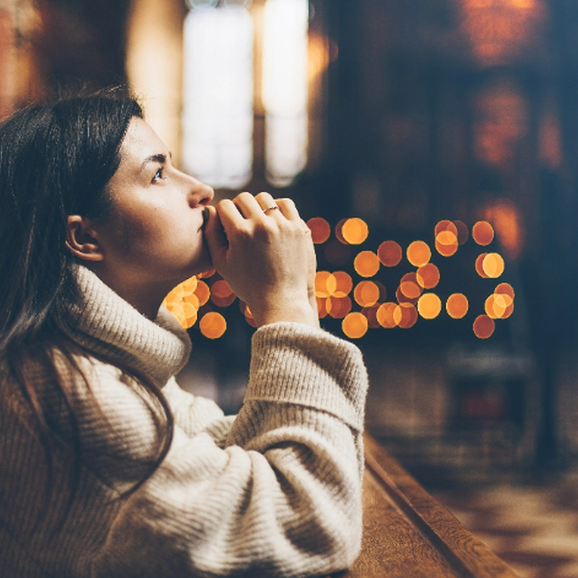 Frau kniend in einer Kirchenbank