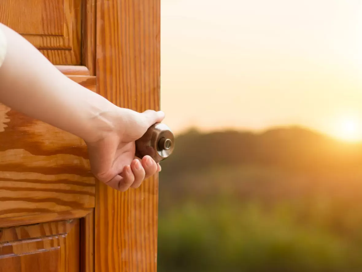 Tür zu einer grünen Wiese mit der Sonne im Hintergrund