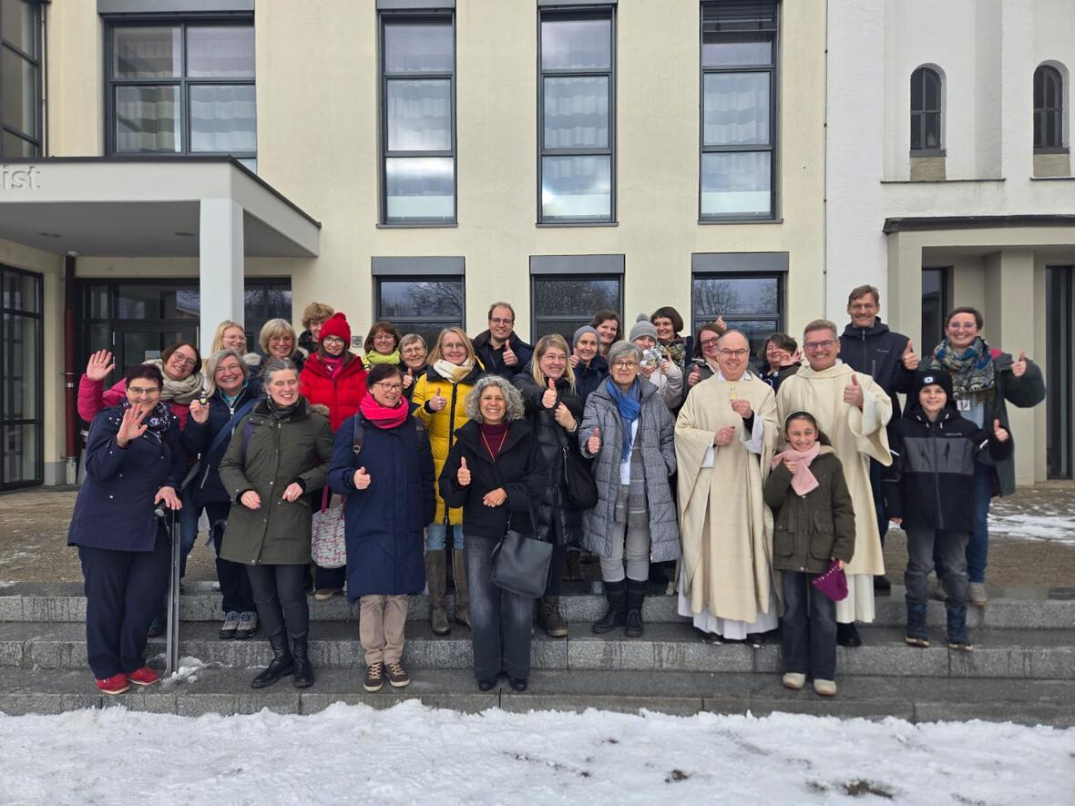 Gruppe von Erwachsenen die die Hand zum Gruß erhoben haben. 
