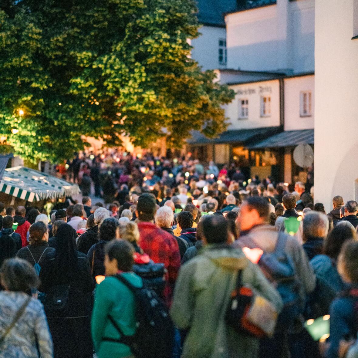 Menschen tragen Kerzen über den Kapellplatz von Altötting und bringen ihren Glauben zum Ausdruck