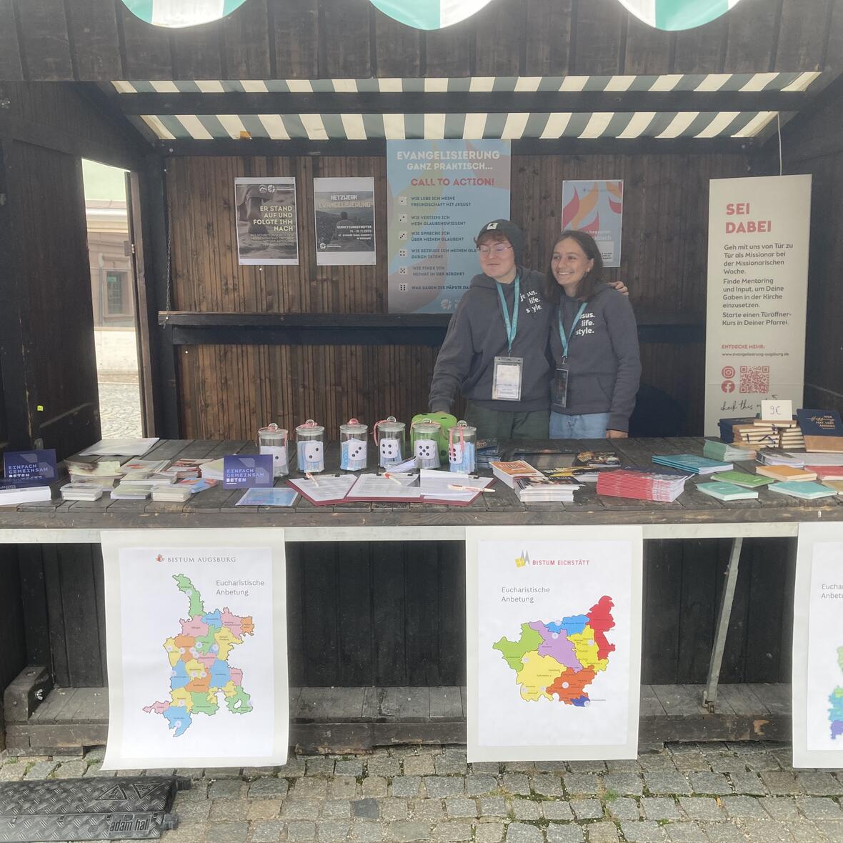 Eine Holzbude mit zwei jungen Missionarinnen auf dem Adoratiokongress in Altötting