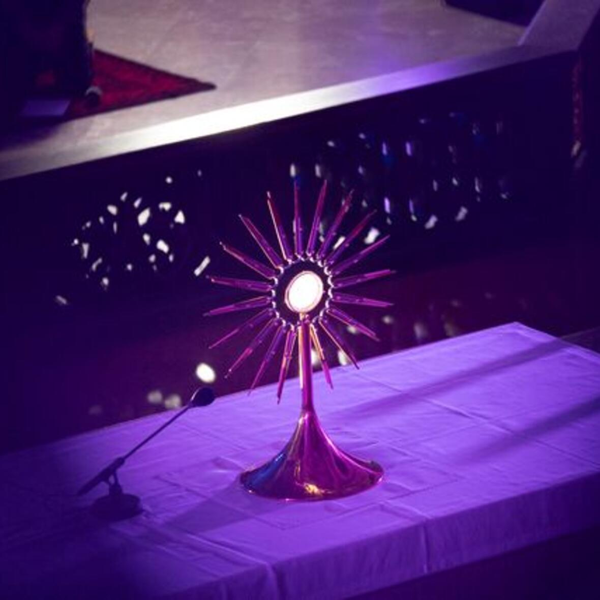 In Blautönen gehaltenes Bild von einer Monstranz die auf einem Altar steht.  