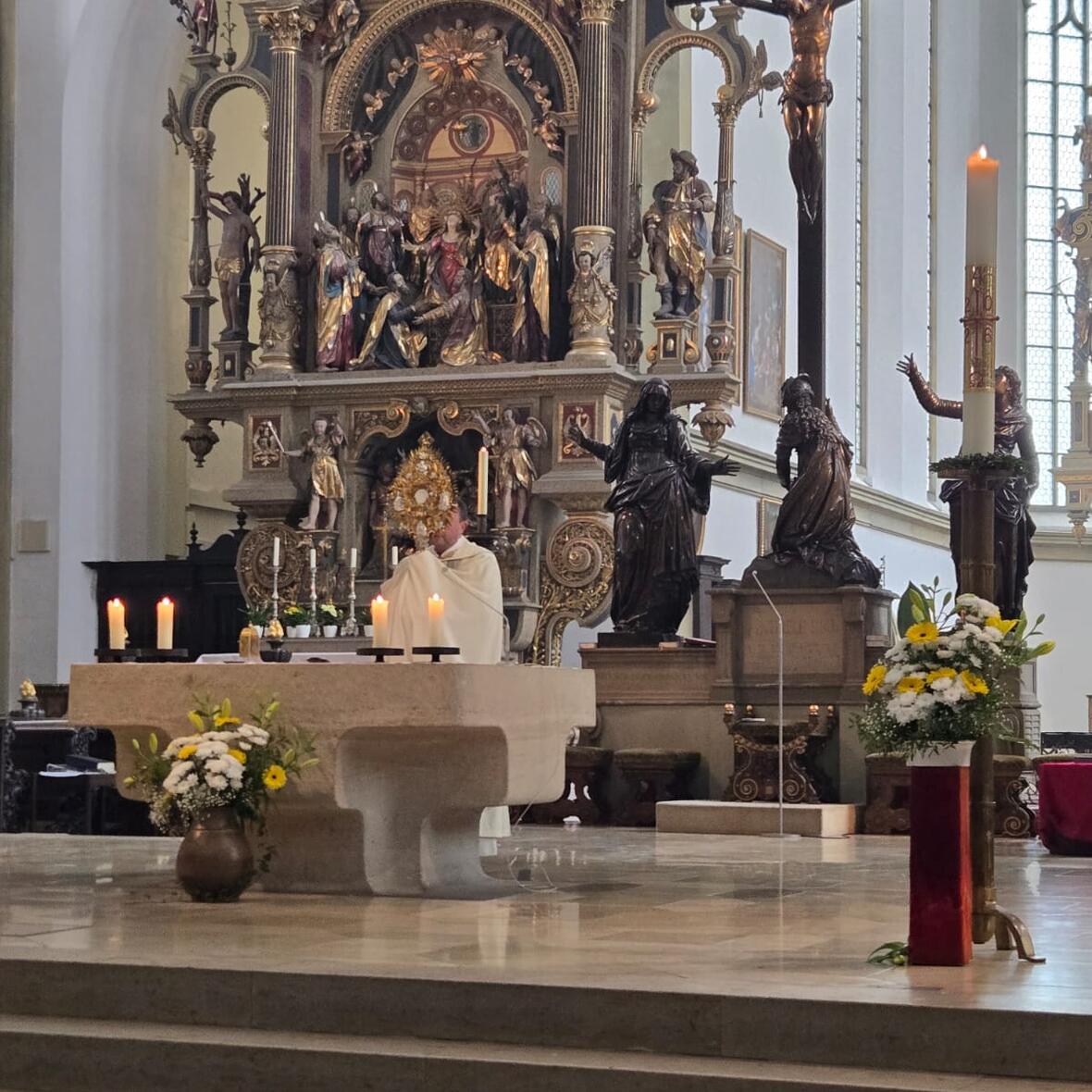 Ein Priester spendet mit einer Monstranz den Segen  im Altarraum von St. Ulrich und Afra, Augsburg