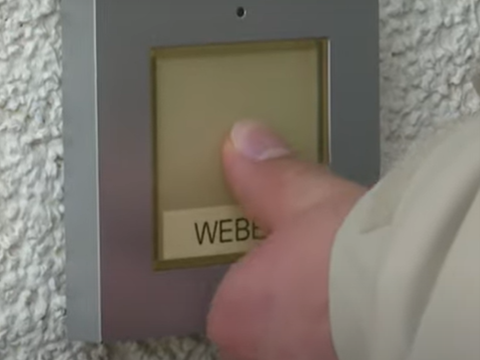Eine Hand betätigt eine Klingel.