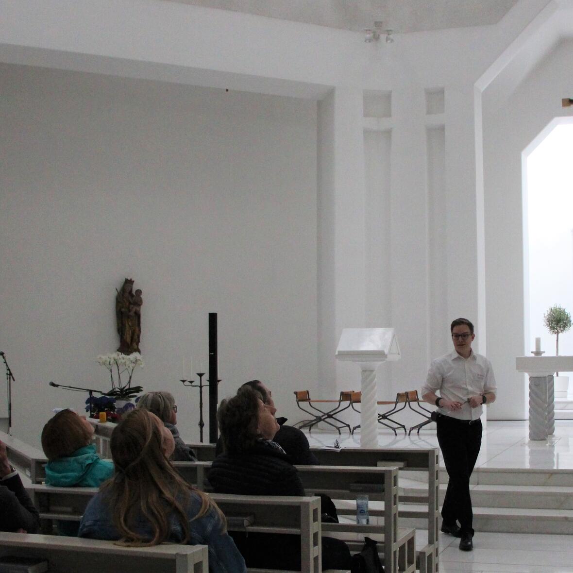 Die Teilnehmer des Workshops blicken zur Decke der Kirche. Der Referent erklärt ihnen das Deckenbild 