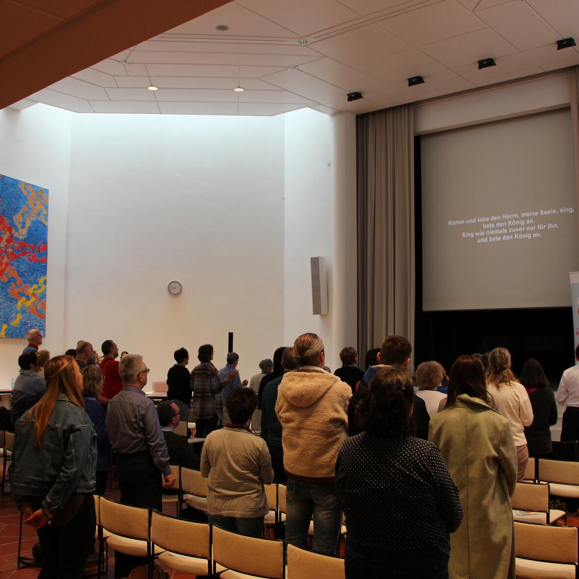 Eine Gruppe von Menschen, die zum Gebet und Lobpreis aufgestanden ist.